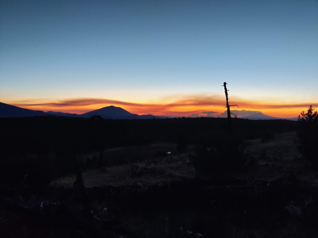 Sunset with wavy shapes of smoke on the horizon