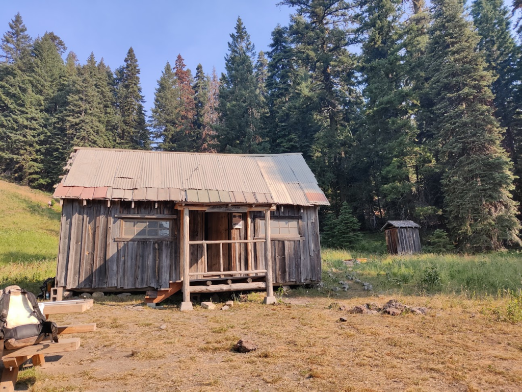 A wooden cabin with an outdoor toilet next to it